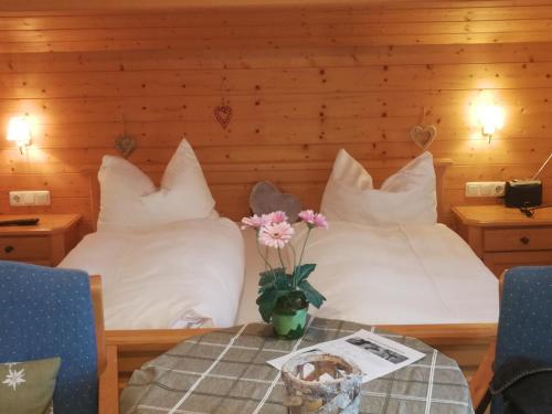 a bedroom with two beds with white pillows and a table at Ferienwohnung Johannesklause in Mittenwald