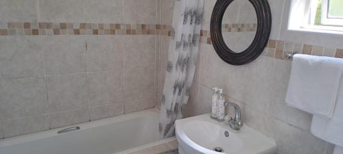 a bathroom with a tub and a sink and a mirror at 18 Key Largo Ocean House of Uzurie in Kingsburgh