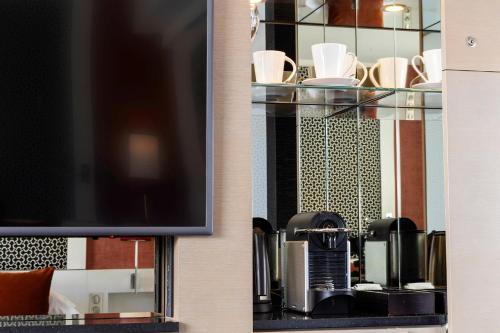 a living room with a tv and chairs at Hôtel Etoile Maillot in Paris
