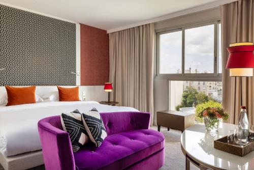 ein Hotelzimmer mit einem Bett und einem lila Sofa in der Unterkunft Hotel Villa Maillot in Paris