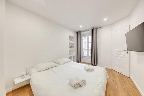 une chambre blanche avec un lit avec des serviettes dessus dans l'établissement L'Orée de Garnier I 1BR I 10 min from Opéra, à Paris