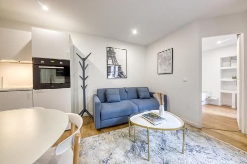 un salon avec un canapé bleu et une table dans l'établissement L'Orée de Garnier I 1BR I 10 min from Opéra, à Paris