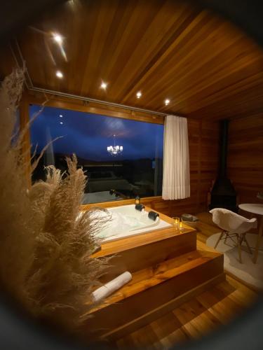 a bath tub in a room with a large window at Romantic Getaway with Jacuzzi and Breakfast in Rancho Queimado in Rancho Queimado