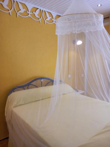 a white bed with a canopy in a room at Villa Mancina in Capesterre-Belle-Eau