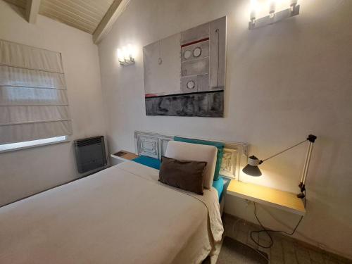 1 dormitorio con 1 cama con lámpara y una pintura en la pared en Cómodo departamento en el bajo neuquino en Neuquén