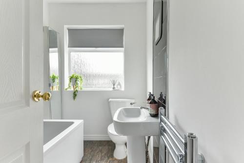 a white bathroom with a sink and a toilet at Fabulous 3 Bedroom House Near Black Country Museum Contractors & families in Tipton