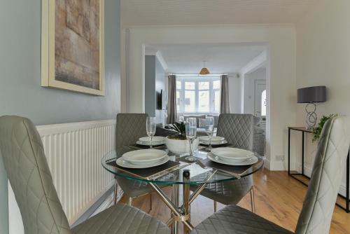 a dining room with a glass table and chairs at Fabulous 3 Bedroom House Near Black Country Museum Contractors & families in Tipton
