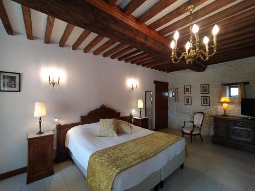 Un dormitorio con una cama grande y una lámpara de araña. en Chambres Résidentielles avec cuisine au Manoir de Mathan à Crépon 5 mn D'Arromanches et 10 mn de Bayeux, en Crépon