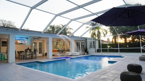 a swimming pool with an umbrella and a house at Home in Miami in Miami