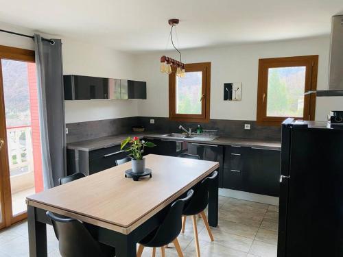 une cuisine avec une table et des chaises en bois, une table et un comptoir dans l'établissement Appartement au pied des cols, à Saint-Jean-de-Maurienne