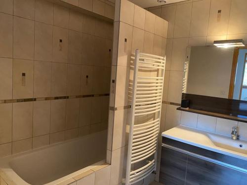 a bathroom with a tub and a sink and a mirror at Appartement au pied des cols in Saint-Jean-de-Maurienne