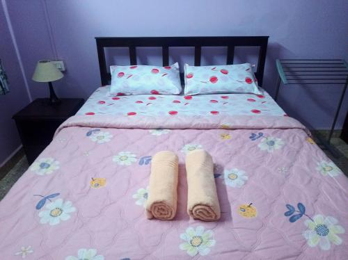 a pink bed with two rolled towels on it at Benirosa Homestay Apartments 2 in Velcao