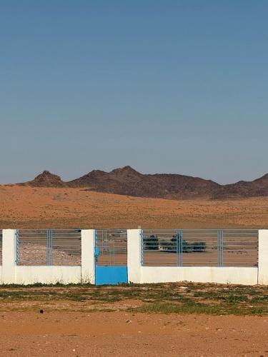 ein Gebäude mit blauen Türen mitten in der Wüste in der Unterkunft مزرعة ود in Al Qā‘id