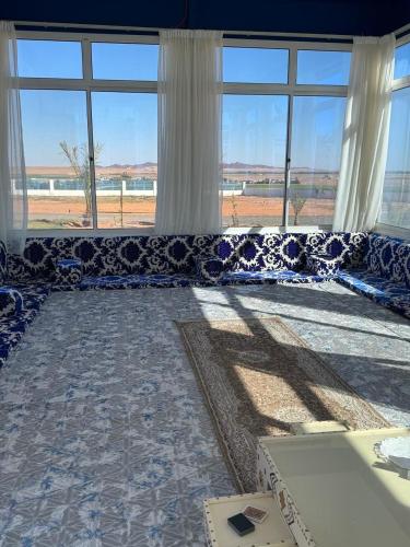 a large living room with a blue couch with windows at مزرعة ود in Al Qā‘id