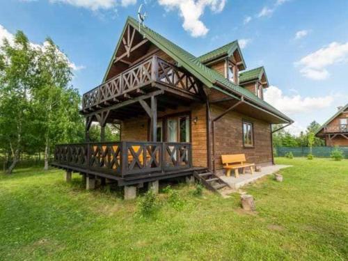 een klein houten huis met een terras op een veld bij Ośrodek Plaża Kownatki in Januszkowo