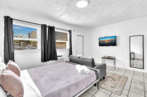a bedroom with a bed and a couch and windows at Executive Studio Hollywood Blvd & Near Beach in Hollywood