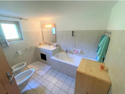 a bathroom with a tub and a toilet and a sink at Alleinstehendes Traumhaus in Poschiavo