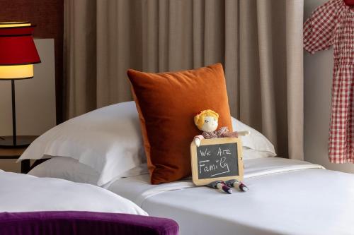 a teddy bear sitting on a bed with a we are family sign at Hôtel Etoile Maillot in Paris