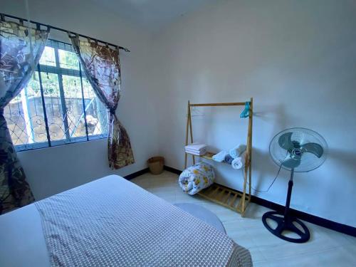 a bedroom with a bed and a window with a fan at Hideaway House in Mwanza