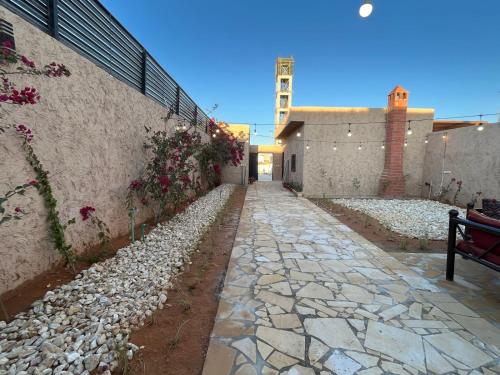 a stone walkway with flowers on the side of a building at شاليهات حائط طيني in Riyadh