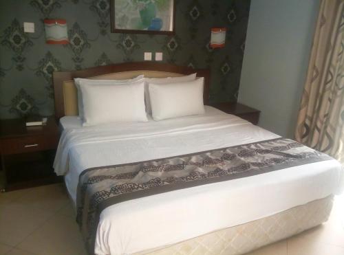 een bed met witte lakens en kussens in een kamer bij Petesville Hotel Limited in Calabar