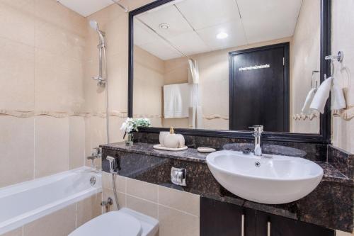 a bathroom with a sink and a toilet and a tub at 3 Bedroom Lake View Apartment in Dubai