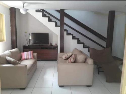 a living room with two couches and a staircase at Casa de Praia - Maria Farinha in Paulista