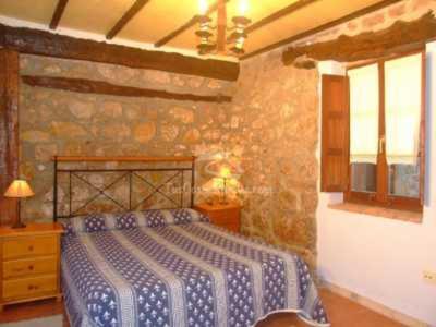 a bedroom with a bed and a stone wall at Bajo el arce del parque de Cabarceno , casa rural in Sobarzo