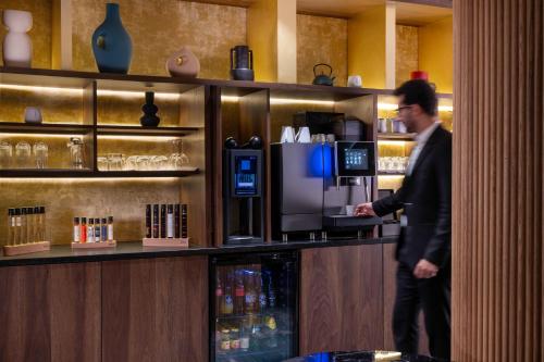 a man standing at the counter of a coffee shop at Hôtel Etoile Maillot in Paris