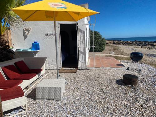a yellow umbrella and chairs and a grill on the beach at The Beach Shack Glamping & The Boat Shed in St Helena Bay