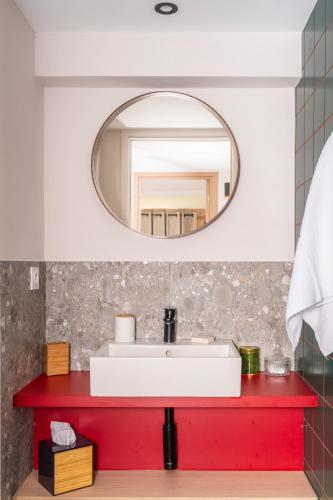 La salle de bains est pourvue d'un comptoir rouge et d'un miroir. dans l'établissement Chalet Nant Rouge, aux Contamines-Montjoie