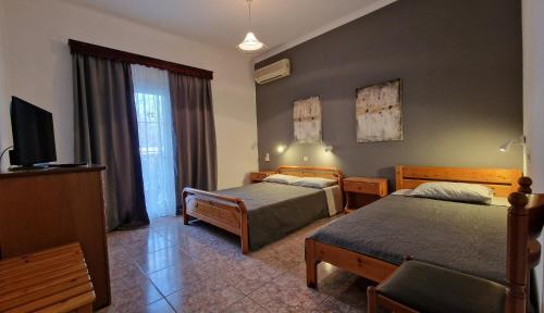 a hotel room with two beds and a television at Villa Dimitris in Paralia Panteleimonos