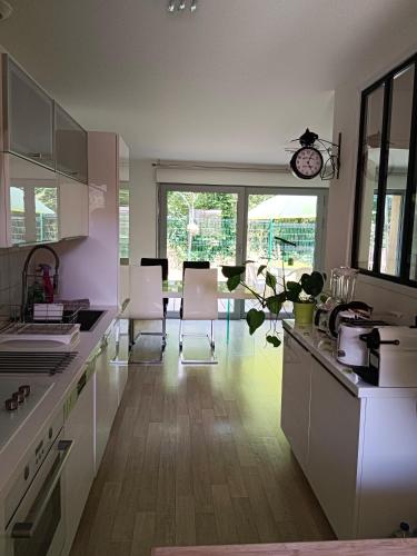 une cuisine avec des armoires blanches et une table et des chaises dans l'établissement Maison en bordure de forêt, à Blanquefort