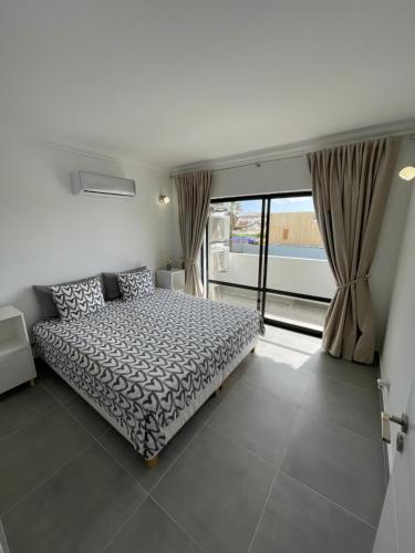 a bedroom with a bed and a large window at Elm Apartament in Sagres