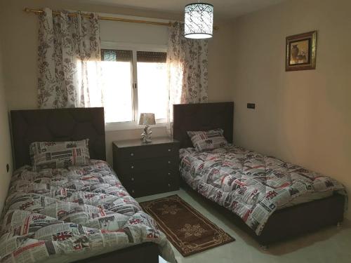 1 dormitorio con 2 camas y ventana en Appartement de luxe centre ville les "Dunes d'Or", en Oujda