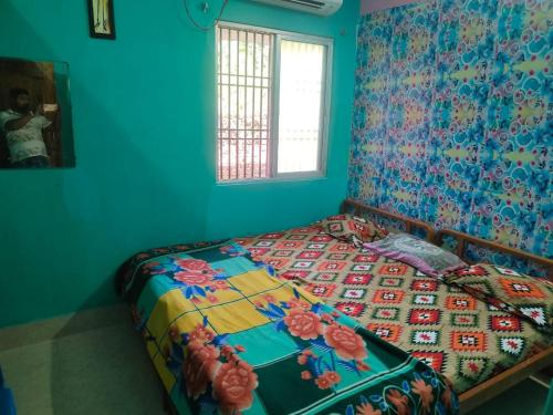 ein Schlafzimmer mit einem Bett mit einer bunten Bettdecke in der Unterkunft JHARANA GUEST HOUSE in Puri