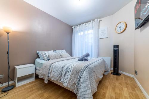 1 dormitorio con 1 cama y reloj en la pared en Grande Île - Apartment near Disneyland Paris, en Meaux