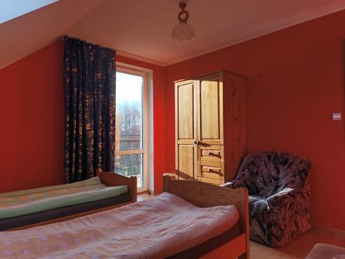 a bedroom with orange walls and a bed and a window at Domek nad stawem z balią i sauną in Sulęczyno