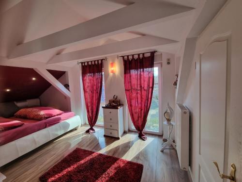 a bedroom with red curtains and a bed and a window at Landhaus Bia in Burig