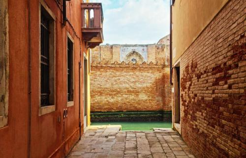 um beco com uma parede de tijolos e um edifício em Pavarotti em Veneza
