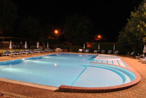 a large swimming pool at night with chairs and tables at Residence Terre Gialle in Castel del Piano