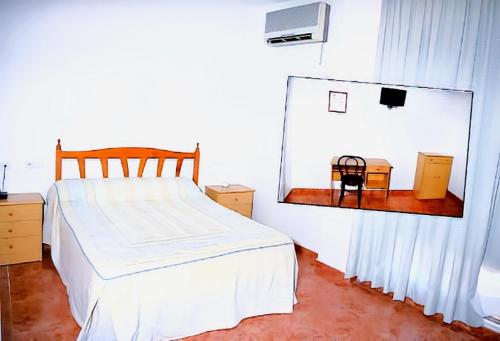 a bedroom with a white bed and a mirror at Hotel y Restaurante Costas in Fortuna