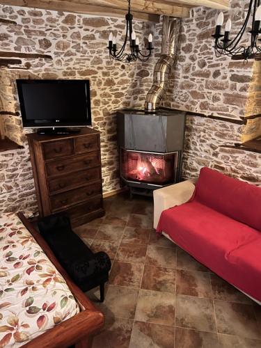 a living room with a fireplace and a red couch at Magical cottage! in Agios Georgios Nilias