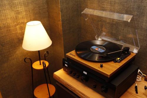 a record player with a vinyl record on a table with a lamp at ゲストホテル宰嘉庵あおい/GuestHotelSAIKAAN_AOI in Maizuru
