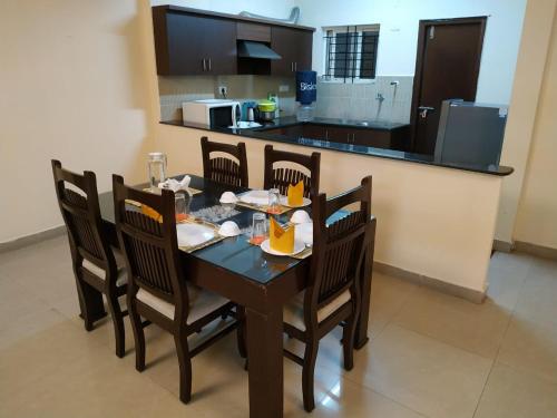 a dining room table with chairs and a kitchen at ADI HOSPITALITY AND TOURS PRIVATE LIMITED in Bangalore