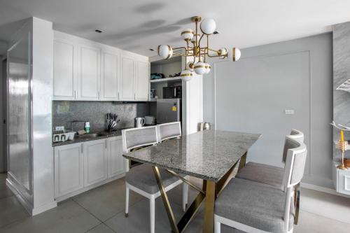 a kitchen with a dining room table and white cabinets at 【Beach Front】海景沙滩别墅，私人泳池，免费早餐，女佣每日清洁，生活方便交通便利 in Phuket Town