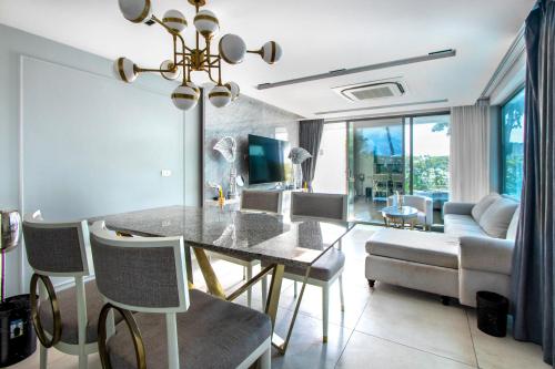 a dining room with a table and a living room at 【Beach Front】海景沙滩别墅，私人泳池，免费早餐，女佣每日清洁，生活方便交通便利 in Phuket Town