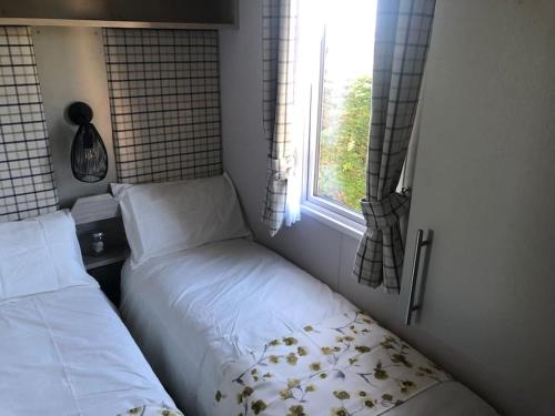 a small bedroom with two beds and a window at Immaculate 2020 Caravan on Newquay Holiday Park in Newquay