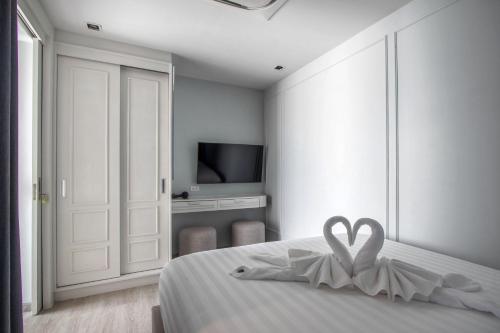a white bedroom with a bed with a heart decoration at 【Beach Front】海景沙滩别墅，私人泳池，免费早餐，女佣每日清洁，生活方便交通便利 in Phuket Town