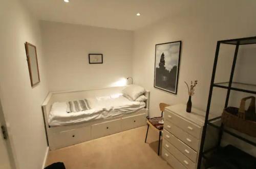 a bedroom with a bed and a dresser in it at Bedroom & dedicated workspace in spacious flat in London